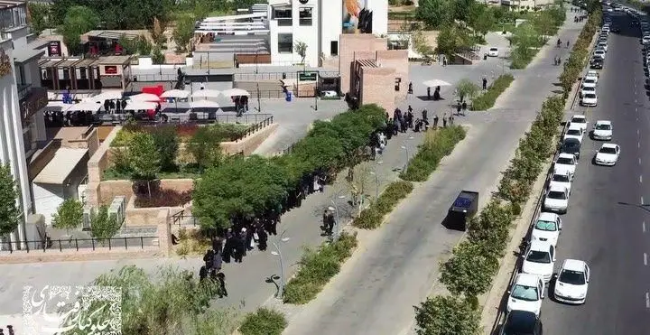 نمای هوایی از رستوران رفتاری، شامل فضای باز پر جنب و جوش با مشتریان، و خیابان شلوغ کنار آن با صف خودروهای پارک شده.