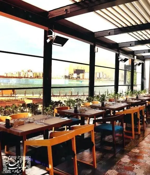 فضای داخلی دنج و دلنشین رستوران رفتاری با میزهای چوبی شیک، پنجره‌های بزرگ و چشم‌انداز بی‌نظیر شهر و دریا.