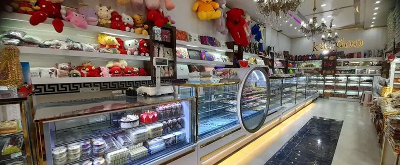 فضای داخلی روشن و جذاب نان شیرینی کندو با ویترین‌های مدرن کیک، شیرینی، دسر، و قفسه‌های متنوع کادو و عروسک‌های فانتزی.