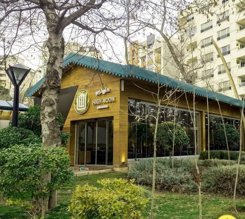 نمای بیرونی رستوران های‌نون با معماری چوبی و سقف سبز در دل فضای سبز و پارک، محیطی آرامش‌بخش برای مشتریان.