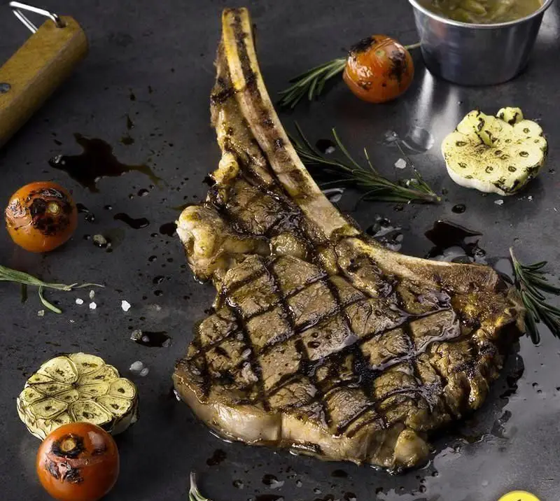 یک استیک گریل شده طعم‌دار و آبدار در رستوران های‌نون، همراه با سیر و گوجه کبابی و رزماری تازه. تجربه‌ای بی‌نظیر از غذای باکیفیت.