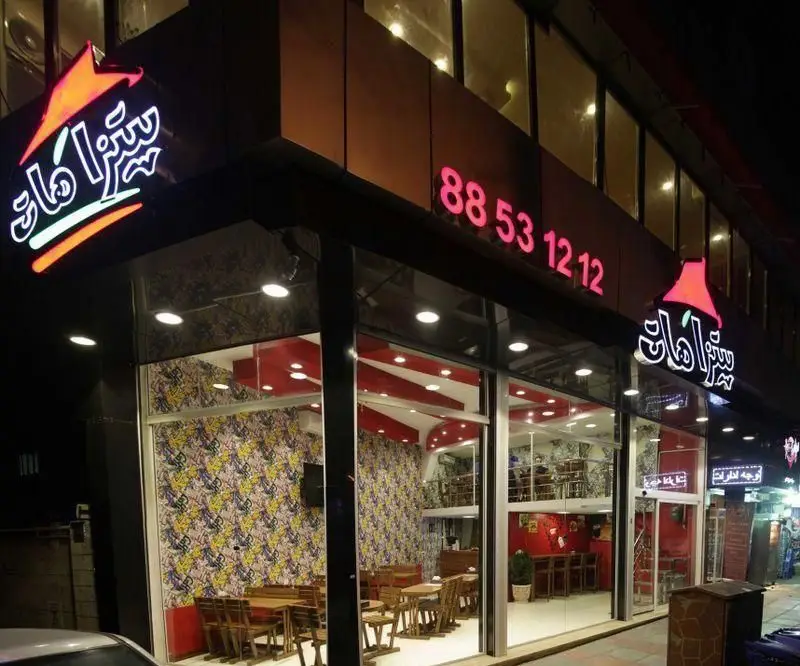 نمای بیرونی و شبانه شعبه پیتزا هات با نورپردازی زیبا و طراحی داخلی مدرن و شیک، همراه با شماره تلفن سفارشات 88531212 برای مشتریان.