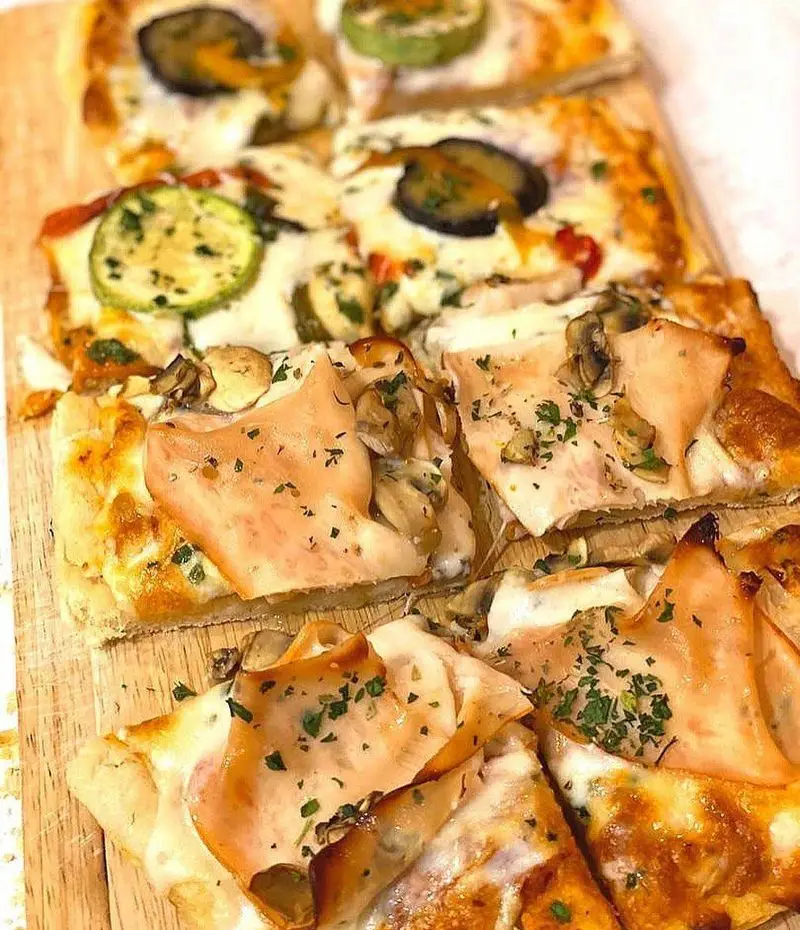 سینی انواع پیتزا لقمه ای خوشمزه از سام استریت تجریش با تاپینگ‌های متنوع سبزیجات، ژامبون و قارچ، مناسب مهمانی و دورهمی.