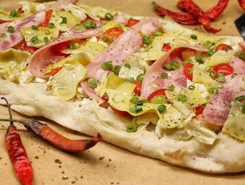 فلت‌برد خوشمزه و خاص سام استریت تجریش با ژامبون، آرتیشو، گوجه گیلاسی و پیازچه، غذایی لذیذ و پرطرفدار در رستوران تجریش.