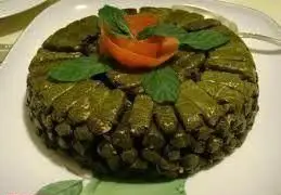 دلمه برگ مو مجلسی تهیه غذا رادان، با تزئین برگ نعنای تازه و گل گوجه فرنگی، غذایی سنتی و خوشمزه برای مجالس شما.