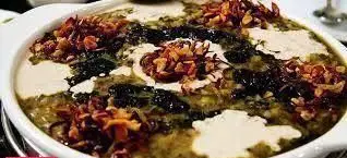 کشک بادمجان مجلسی تهیه غذا رادان با تزیین نعناع داغ و پیاز داغ، غذایی لذیذ و سنتی برای پذیرایی از مهمانان شما.