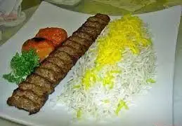 یک پرس چلوکباب کوبیده مجلسی و خوش‌طعم با برنج زعفرانی، گوجه کبابی و سبزیجات معطر از تهیه غذا رادان.