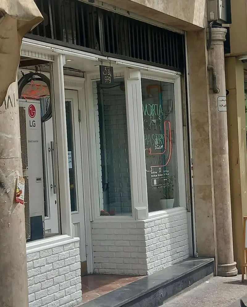 نمای خارجی کافه قنادی کیک ورتا (VORTA PASTRY) با دیوار آجری سفید، درب شیشه‌ای و نئون جذاب، پلاک 979، محل عرضه بهترین کیک و شیرینی تازه.