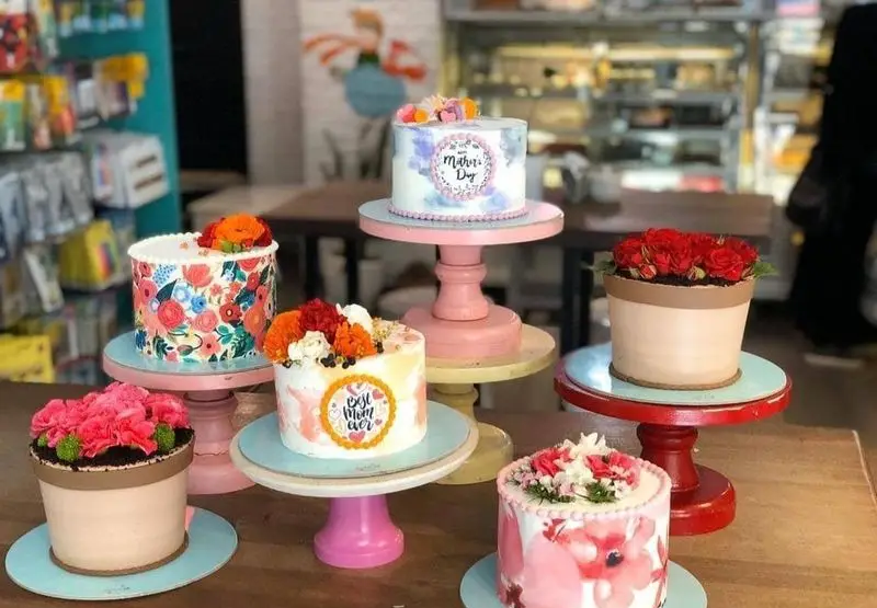 مجموعه کیک‌های فانتزی و دست‌ساز کافه قنادی کیک ورتا با تم روز مادر. شامل کیک‌های گلدان گل و طرح‌های هنری مناسبتی.