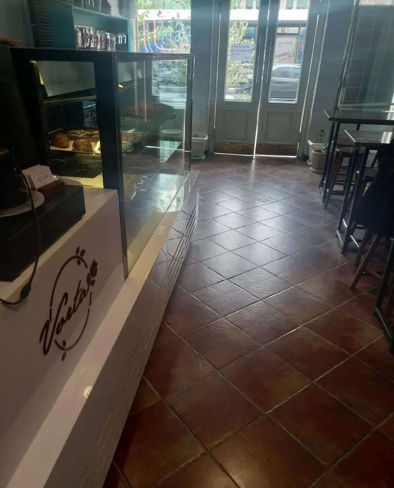 تصویری از فضای داخلی دلنشین و دنج کافه قنادی کیک ورتا، با ویترین‌های جذاب شیرینی و میز و صندلی‌های راحت برای مشتریان.