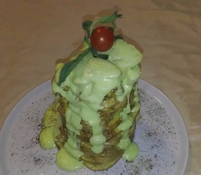 بشقابی از دسر یا غذای خاص کافی شاپ رویال، شامل برش‌های انباشته شده با سس سبز و تزیینات گیلاس و برگ نعنا، ایده‌آل برای مشتریان.