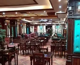 نمای داخلی کافی شاپ رویال با دکوراسیون سنتی، میزها و صندلی‌های چوبی زیبا، نورپردازی گرم و فضایی دنج و دلنشین مناسب قرارهای دوستانه و کاری.