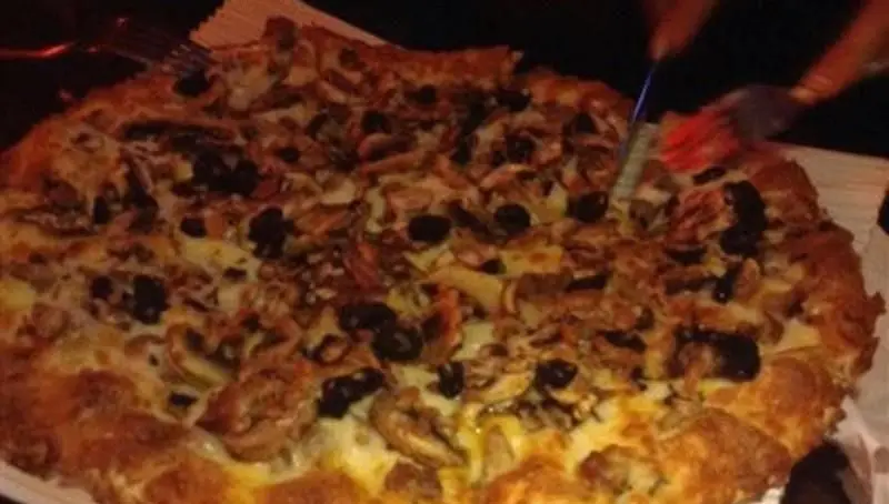پیتزای بزرگ و لذیذ رستوران ایتالیایی رز ایتالیایی با قارچ، زیتون سیاه و پنیر فراوان در حال برش خوردن، مناسب برای هر سلیقه.