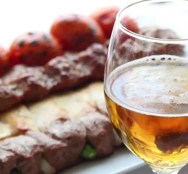 تجربه غذای اصیل ایرانی در چلو کباب نایب: یک لیوان دلستر خنک کنار سیخ‌های کباب کوبیده و گوجه کبابی لذیذ.