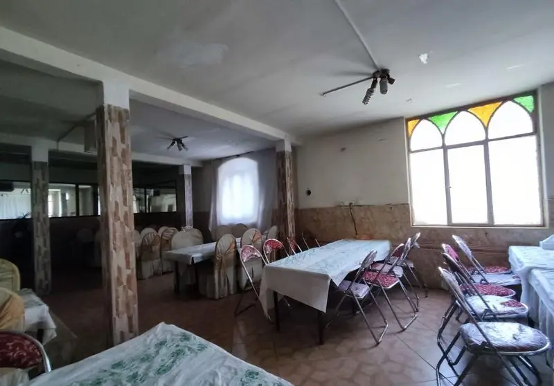 فضای داخلی رستوران حامدی با میز و صندلی‌های چیده شده، مناسب برگزاری مهمانی و مراسم. پنجره رنگی زیبا به سالن جلوه خاصی داده است.