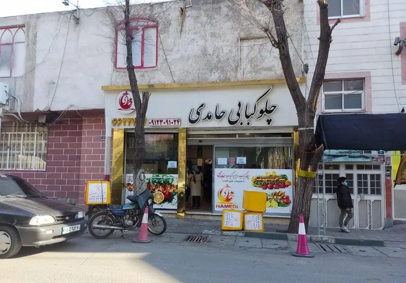 تصویر نمای جلویی رستوران و چلوکبابی حامدی، با تابلوی بزرگ نام و شماره تماس، و تبلیغات جذاب انواع کباب‌های ایرانی.