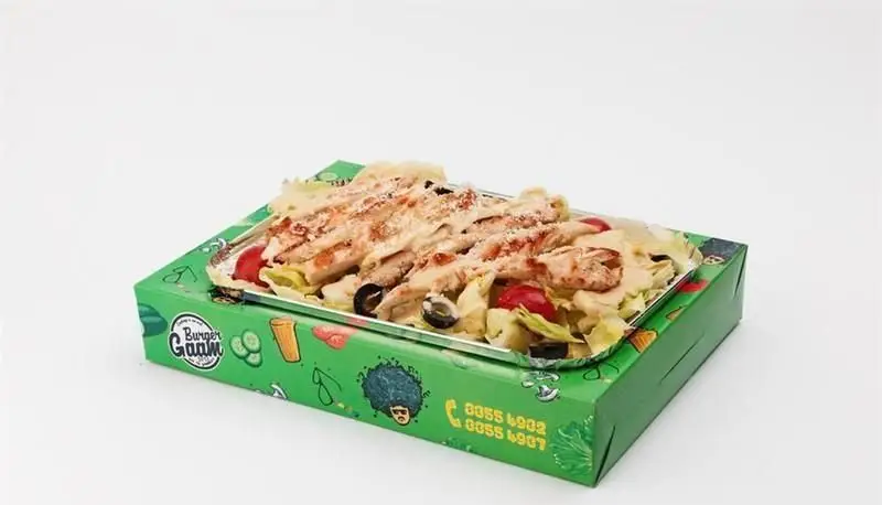 سالاد سزار با فیله مرغ گریل شده و سس مخصوص برگر گام برگر، به همراه زیتون و سبزیجات تازه، روی جعبه سبز لوگودار رستوران.