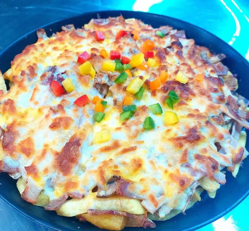 سیب زمینی پنیری ویژه فست فود آرام ناز با پنیر ذوب شده، بیکن و فلفل دلمه‌ای رنگارنگ. انتخابی ایده‌آل برای دوستداران طعم‌های خاص.