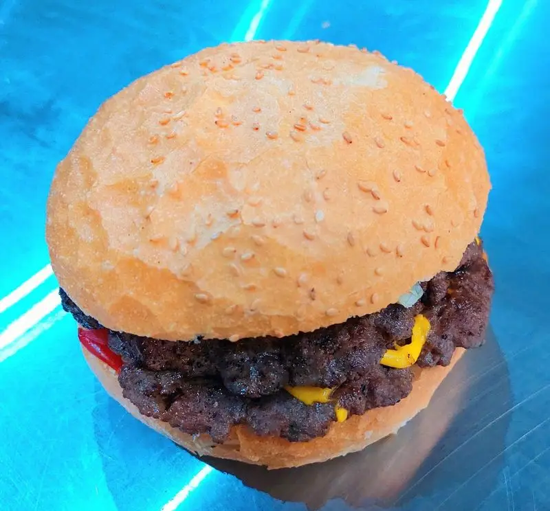 همبرگر دوبل آبدار و لذیذ فست فود آرام ناز، با نان کنجدی تازه و پنیر ذوب شده، یک غذای فست فودی هیجان‌انگیز و خوشمزه.