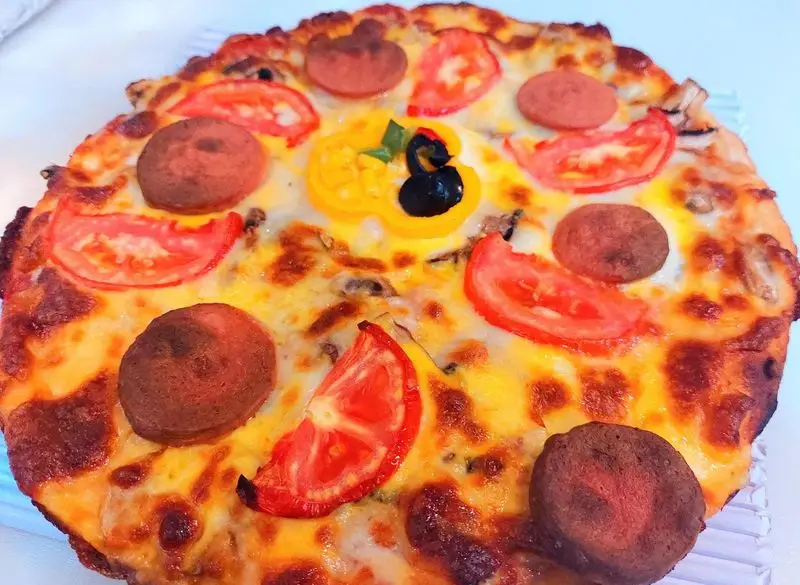 پیتزا خوشمزه و داغ فست فود آرام ناز با پنیر فراوان، گوجه، سوسیس و قارچ؛ انتخابی عالی برای یک وعده غذایی دلچسب.