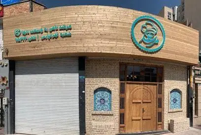 نمای بیرونی رستوران مرشد با تابلوی چوبی، لوگوی آبی، درب چوبی سنتی و پنجره‌های طاق‌دار با کاشی‌کاری آبی رنگ، فضایی دلنشین و دعوت‌کننده.