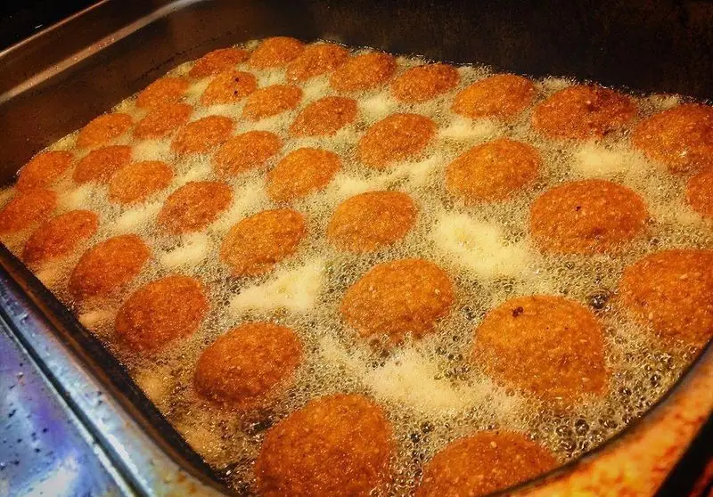 فست فود شاورما یاس: کوفته یا فلافل‌های تازه و ترد و طلایی‌رنگ در حال سرخ شدن در روغن داغ، آماده برای یک وعده غذایی لذیذ.