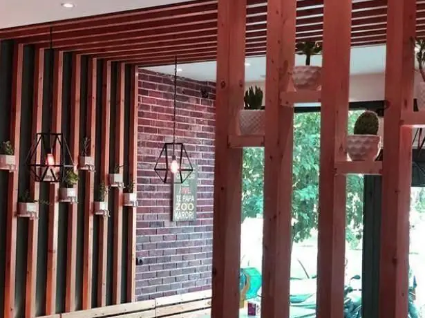 فضای داخلی گرم و جذاب پیتزایی پاروت با طراحی چوبی و نورپردازی مدرن. شامل گلدان‌های کوچک و دیوار آجری برای تجربه‌ای لذت‌بخش.