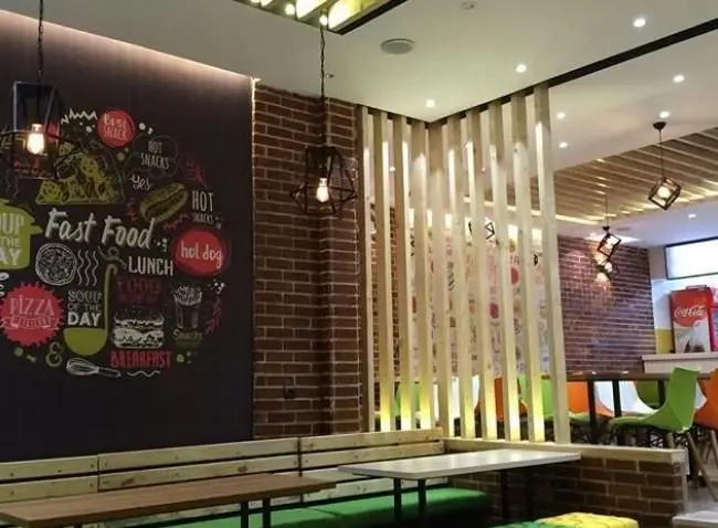 فضای داخلی پیتزایی پاروت با دکوراسیون فست فود مدرن، دیوارهای آجری و تابلو گچی منوی جذاب غذاها، شامل پیتزا و هات داگ.
