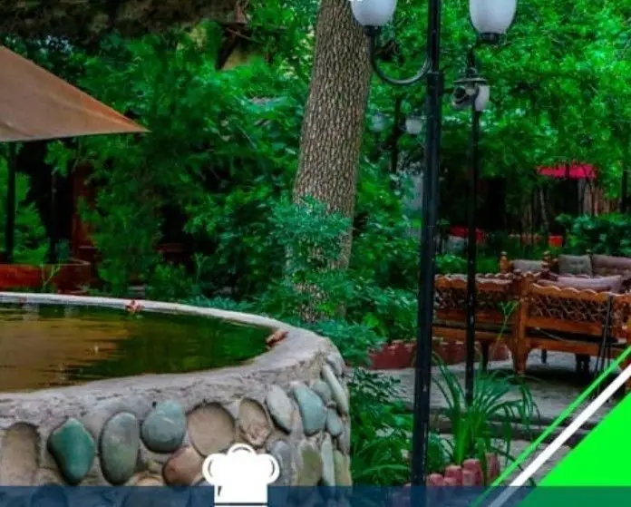 فضای دلنشین باغ رستوران شادی با حوضچه آب، درختان سرسبز، مبلمان چوبی شیک و نورپردازی مناسب برای گذراندن اوقاتی خوش.