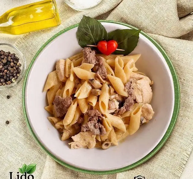 پاستا پنه خامه‌ای لذیذ رستوران ایتالیایی لیدو، شامل مرغ، گوشت، قارچ، زیتون، سس مخصوص و تزئین ریحان. ایده‌آل برای عاشقان پاستا.
