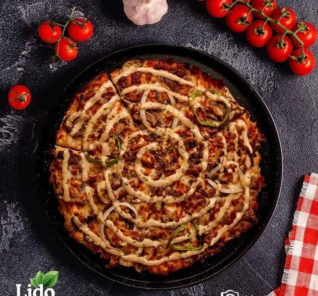 پیتزای لذیذ و دلپذیر رستوران ایتالیایی لیدو با تاپینگ‌های گوشت، قارچ، پیاز، فلفل دلمه و سس مخصوص، چیدمان هنرمندانه.