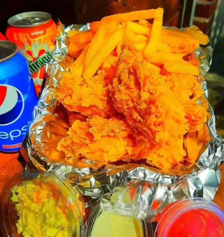 مرغ سوخاری و سیب زمینی سرخ کرده خوشمزه از ساندویچ های حمید و مجید با نوشابه و انواع سس، انتخابی عالی برای یک وعده غذایی.