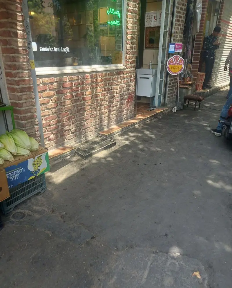 ورودی جذاب ساندویچ حمید و مجید با نمای آجری، همراه با سبزیجات تازه، تابلو پیتزا و امکان سفارش آنلاین اسنپ فود.