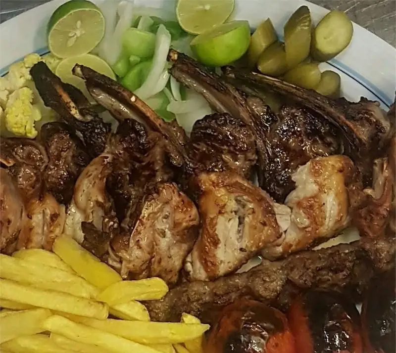 تصویر غذای لذیذ ایرانی شامل انواع کباب (شیشلیک، جوجه کباب، کوبیده) با دورچین سیب‌زمینی، لیمو و ترشی در رستوران ایرانی استخر ونک