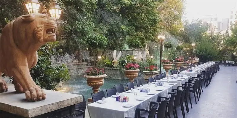 نمایی از فضای باز و زیبای رستوران ایرانی استخر ونک، مناسب برگزاری مراسم و مهمانی‌ها با دکوراسیون چشم‌نواز، آبنما و مجسمه شیر.