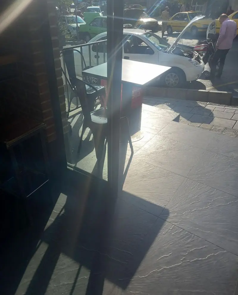 محیط بیرونی فست فود گامبی ساندویچ با میز و صندلی‌های شیک در فضای باز کنار خیابان، مناسب لذت بردن از ساندویچ‌های خوشمزه.