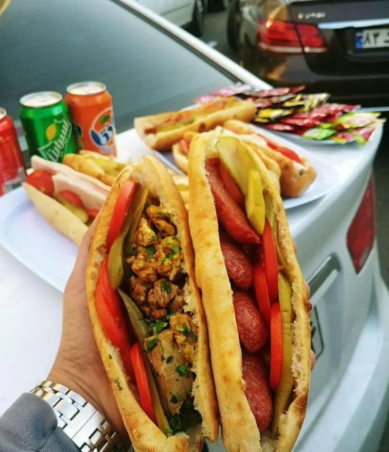 انواع ساندویچ‌های پرطرفدار اغذیه یگانه: هات داگ، سوسیس و مرغ، با مخلفات تازه و نوشیدنی‌های خنک. لذت یک وعده سریع و خوشمزه.