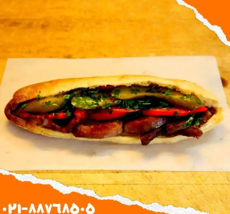 ساندویچ خوشمزه و تازه اغذیه یگانه شامل نان باگت، گوشت، گوجه، خیارشور و سبزیجات معطر. آماده سفارش تلفنی.