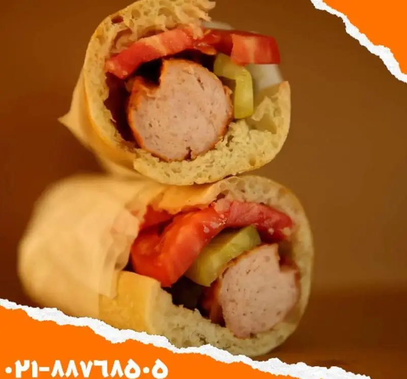 ساندویچ سوسیس ویژه اغذیه یگانه: دو ساندویچ برش‌خورده پرملات با سوسیس، گوجه و خیارشور تازه در نان باگت. سفارش از فست فود یگانه.