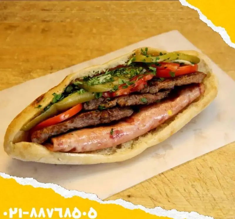 ساندویچ اغذیه یگانه: ترکیبی لذیذ از گوشت ورقه‌ای گریل، سوسیس، ترشی، گوجه و سبزی تازه. غذایی پرطرفدار و خوشمزه!