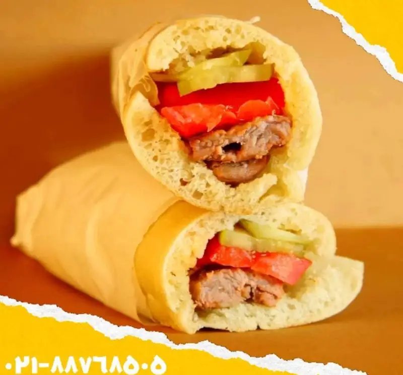 ساندویچ مخصوص گوشت اغذیه یگانه، در نان باگت تازه، با برش‌های گوشت لذیذ، گوجه و خیارشور، پیچیده شده در کاغذ آماده سرو.