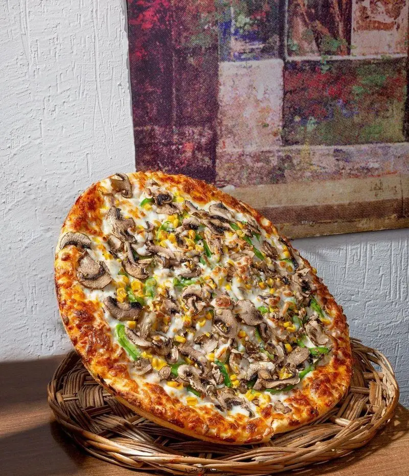 پیتزا قارچ، ذرت و فلفل دلمه ای تازه و داغ از "پیتزا در ب در" با پنیر آب شده فراوان و نان برشته، لذتی بی‌نظیر برای شما.