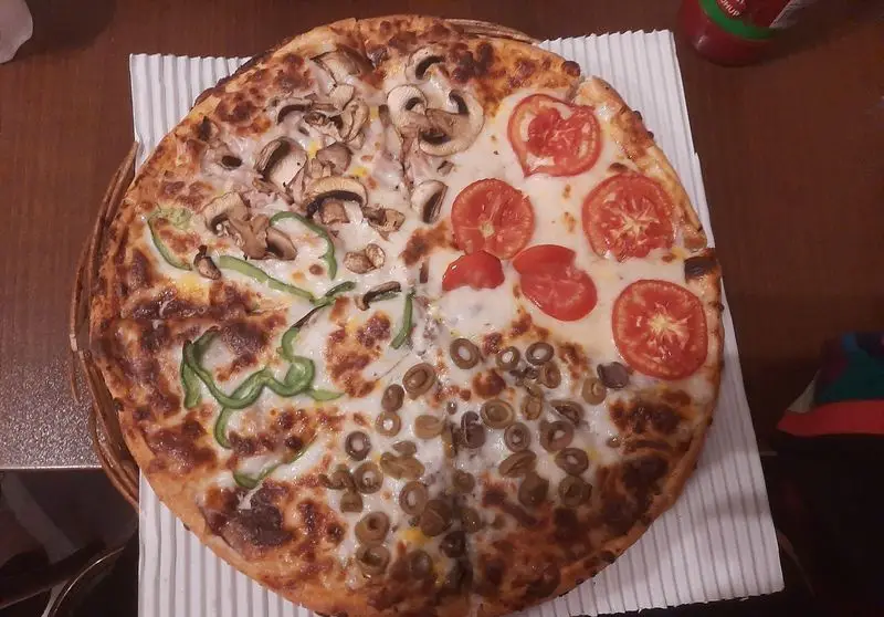 پیتزا چهارفصل بزرگ و اشتها آور از پیتزا در ب در شامل قارچ، فلفل دلمه سبز، گوجه فرنگی تازه و زیتون.