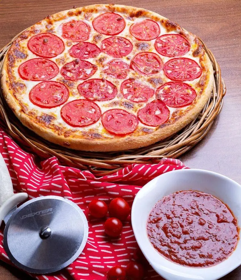 پیتزا در ب در: پیتزای اصیل با پنیر و لایه‌های گوجه تازه، همراه با سس مخصوص و گوجه گیلاسی. انتخابی عالی برای سئو.