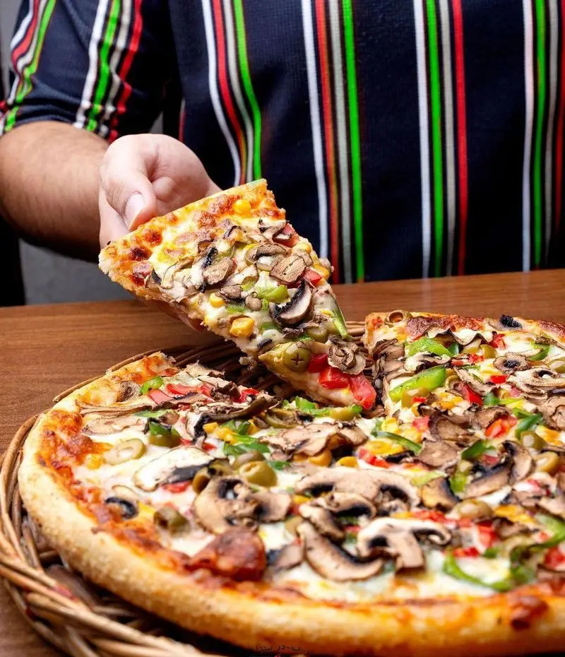 سفارش پیتزای سبزیجات ویژه و خوشمزه از پیتزا در ب در شامل قارچ، فلفل دلمه‌ای، ذرت و زیتون، آماده برای لذت بردن در منزل.