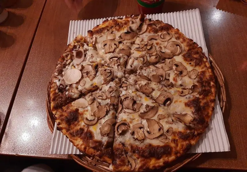 تصویر با کیفیت از پیتزا قارچ بزرگ و خوشپخت پیتزا در ب در، با پنیر آب شده و قارچ‌های تازه، لذت طعم بی‌نظیر.