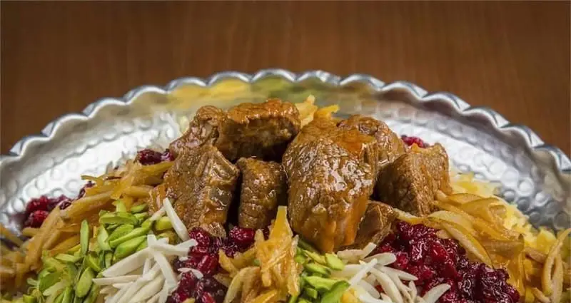 تصویری از غذای لذیذ و مجلسی چلوگوشت یا باقالی پلو با گوشت گوسفندی، تزیین شده با زرشک، خلال پسته و بادام، از منوی رستوران مسینه.
