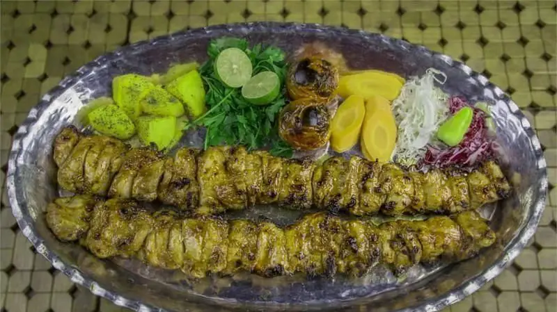 سینی کباب جوجه لذیذ رستوران مسینه با دورچین کامل شامل گوجه کبابی، گوجه سبز، سبزیجات تازه، ترشی و لیمو، مناسب ناهار و شام.