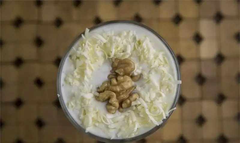 تصویری جذاب از دسر یا نوشیدنی خامه ای رستوران مسینه، تزیین شده با گردو و تکه های سفید، طعمی بی نظیر از منو.