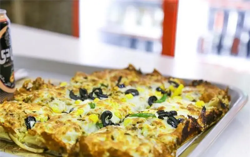 پیتزا مخصوص آمادو با پنیر فراوان، ذرت، زیتون سیاه و فلفل سبز، به همراه نوشابه خنک در فست فود آمادو.